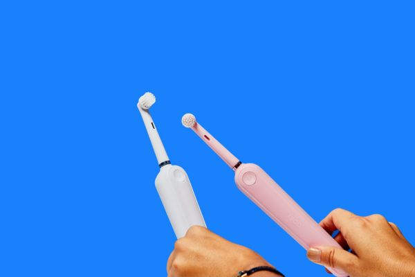 Cepillos de dientes eléctricos blancos y rosas sobre fondo azul