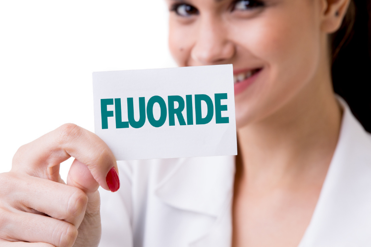 Ein Arzt hält eine Karteikarte mit der Aufschrift „Fluorid“ hoch